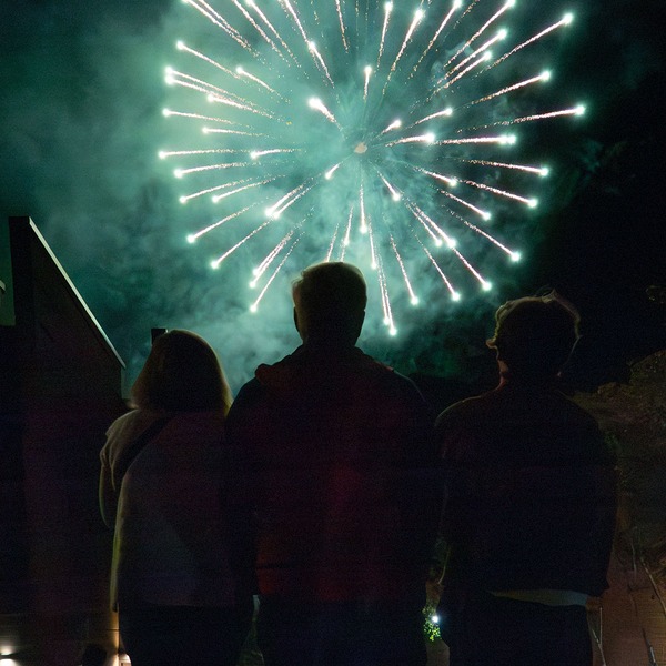 Photo of people looking up at fireworks in the sky.