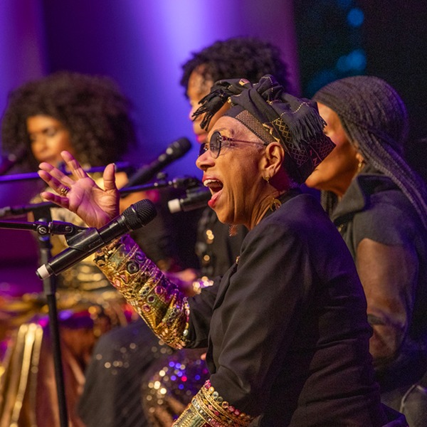 Musicians perform on a stage and sing into microphones.  