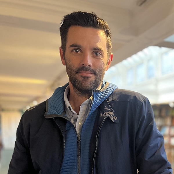 Professor of Sociology Andrew Lindner standing indoors, wearing a jacket and looking at the camera.