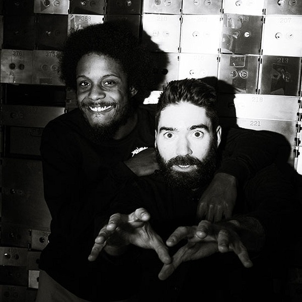 Two individuals smile for a photo with dim lighting.   