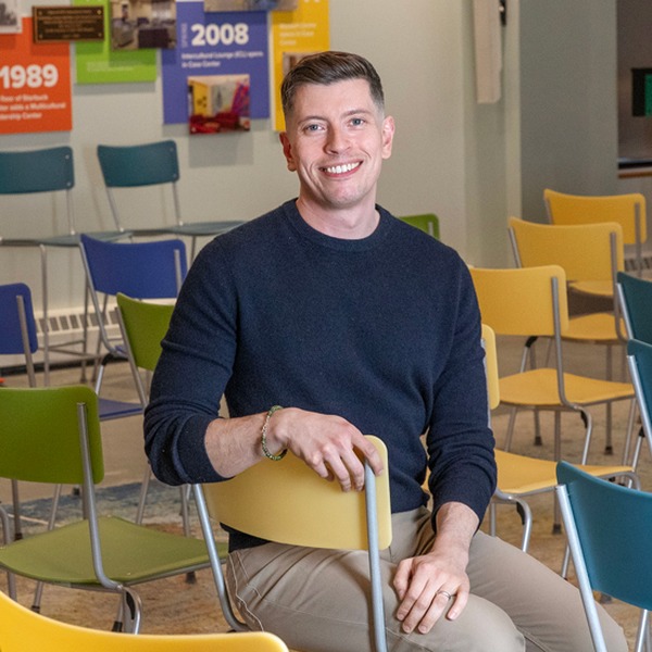 Fred Braunstein sits in a chair in a classroom.