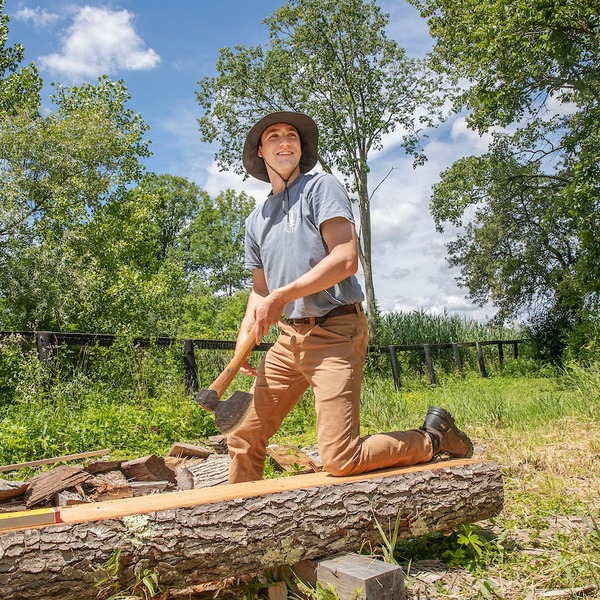 Photo of student Jonah Cadorette '26 smiling while chopping wood.