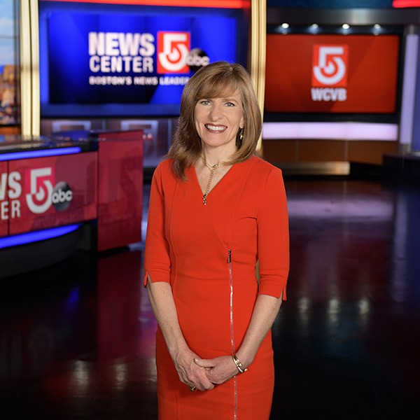 Margaret Cronan stands in a television news studio, smiling at the camera