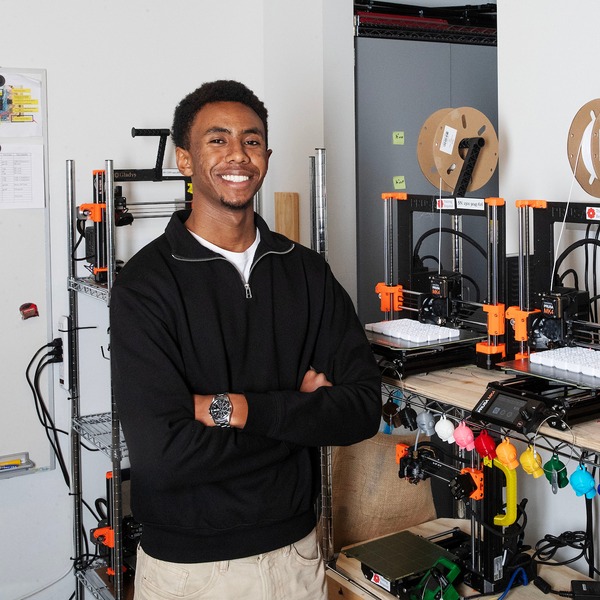 Թ student Isiah Karitanyi smiles for a photo standing in a lab.